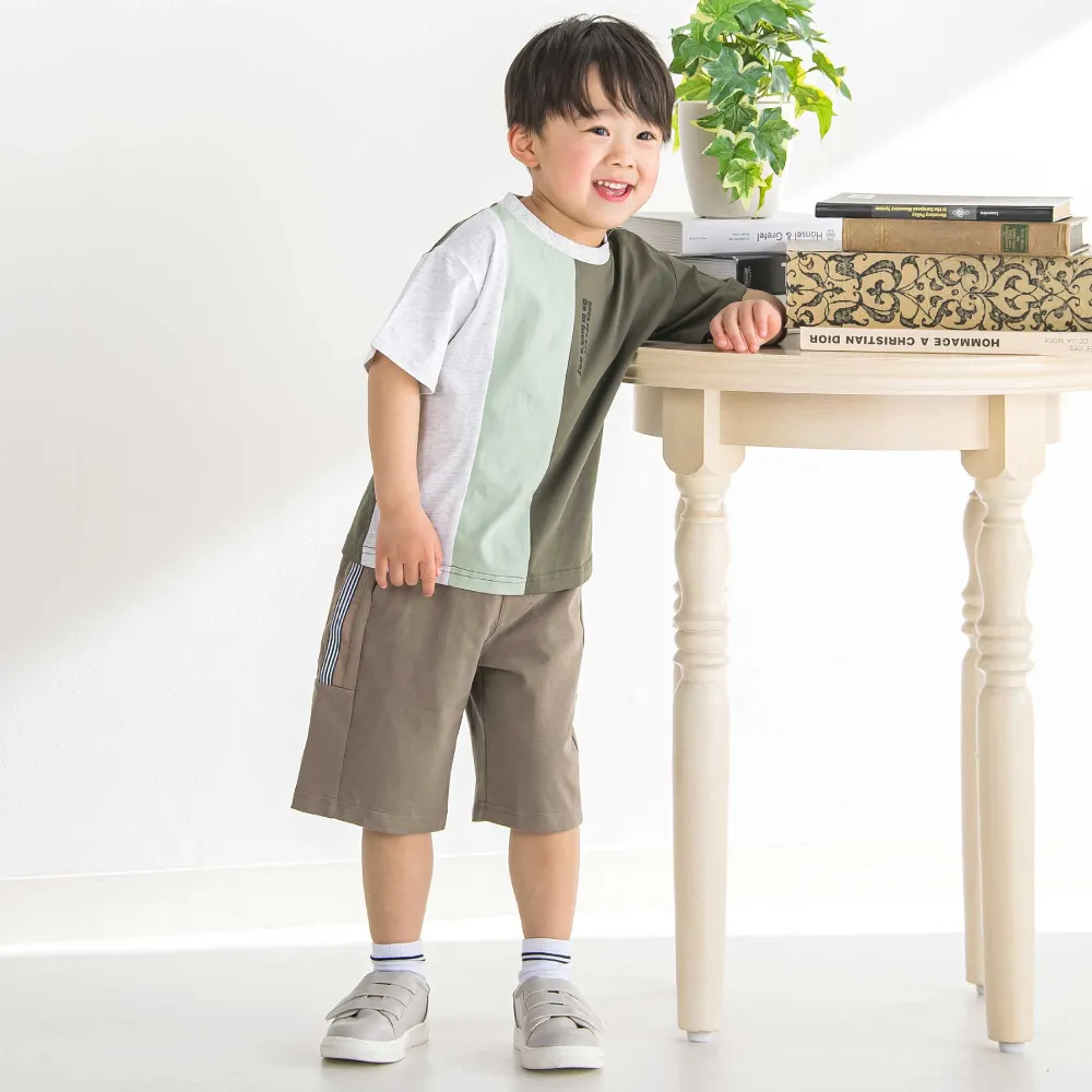 グリーン配色Tとベージュパンツを着用した男の子の全身コーディネートスタイル
